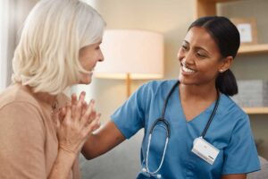 A nurse assists an older adult with reviewing medications at a table in a comfortable residential setting.