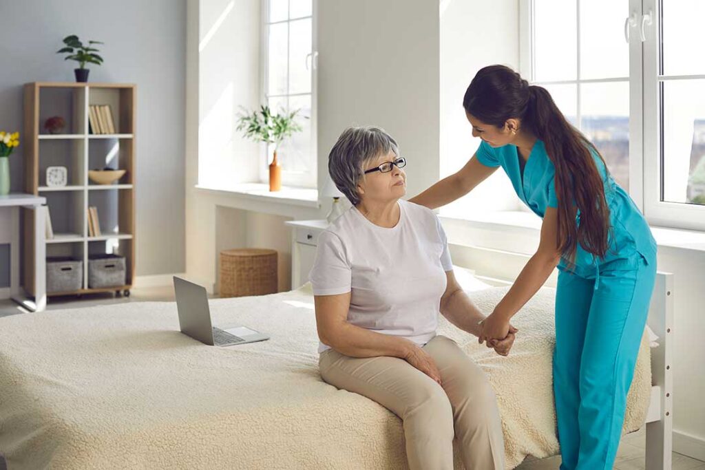 Two older adults talking with family members across a small table in a bright, comfortable lounge area.