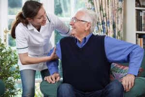 Older adult choosing breakfast while a caregiver reviews a daily routine at a bright dining table.