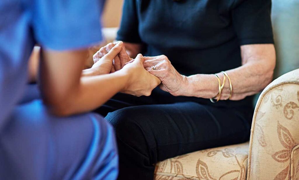 Older adult and family member reviewing advance care documents at a kitchen table with a physician nearby.